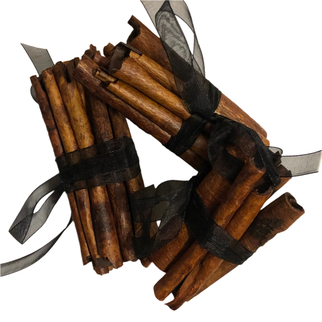 Bundles of cinnamon sticks tied with black ribbons on a white background