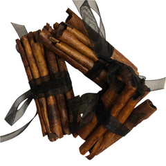 Bundles of cinnamon sticks tied with black ribbons on a white background