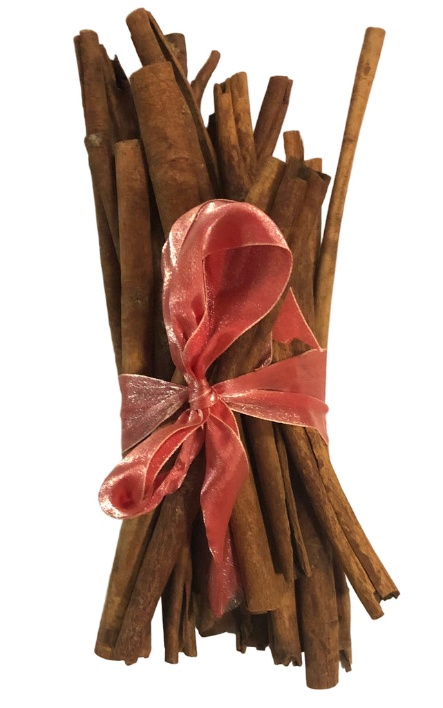 Bunch of cinnamon sticks tied with a pink ribbon on a white background