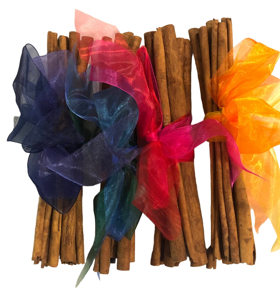 Bundles of cinnamon sticks with colorful ribbons on a white background