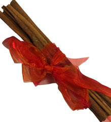 Cinnamon sticks tied with a red ribbon on a white background