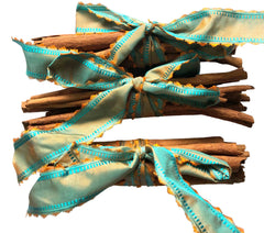 3 bundles of cinnamon sticks tied with two matching fabric ribbons in bows, shown on a plain white background.